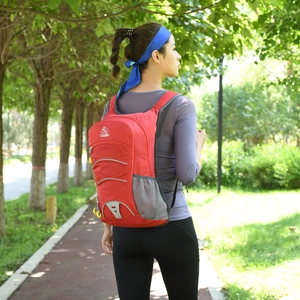 Red lightweight outdoor backpack for hiking and cycling worn by a model in nature