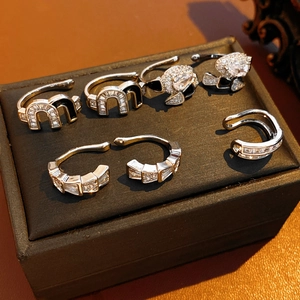 Detailed view of silver and gold zircon ear cuffs including M logo and snake designs