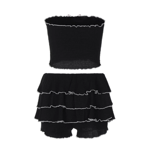 Détail d'un ensemble noir deux pièces montrant le tissu plissé et bords ondulés argentés