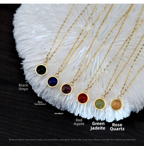 Macro detail of various natural gemstone pendants including onyx and quartz on gold chains