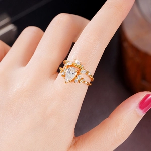 Detail of a pear-cut zircon gold ring set with sparkling stones on the finger