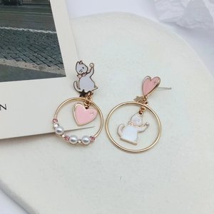 Detail of asymmetrical cat heart earrings with pink stones and pearls on a white tray