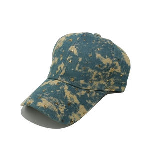 Detail of denim baseball cap with gold star moon studs and blue yellow tie-dye wash