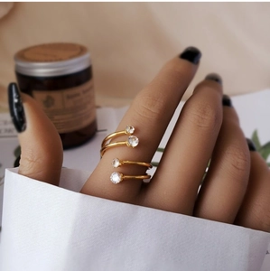 Close-up of golden spiral open ring with zircons worn on hand against a vintage background