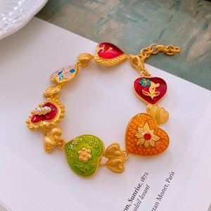 Macro view of vintage golden bracelet with colorful enamel heart charms and pearl inlay
