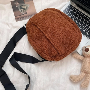 Brown fleece crossbody bag with adjustable black strap shown in a cozy lifestyle setting