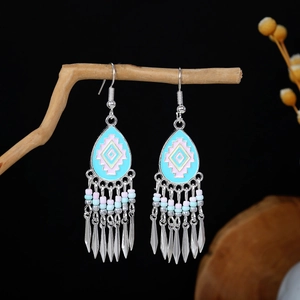 Detail of silver ethnic earrings with blue enamel, colorful beads and leaf tassels