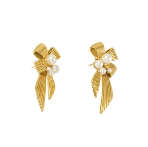 Detail of golden bow earrings with textured surface and elegant white pearls