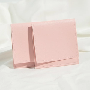 Detail view of two pink PU leather pouches with flap closure on white fabric background