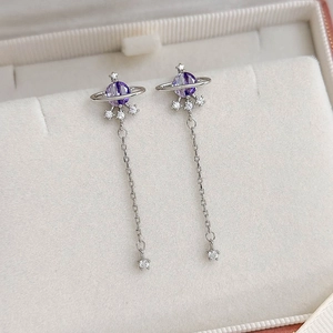 Detailed macro view of purple saturn earrings with long silver tassel chains and zircons