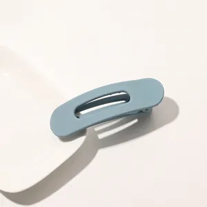 Close-up of matte grey-blue duckbill hair clip on a minimalist white ceramic plate
