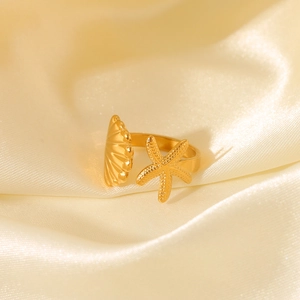 Detail of gold starfish and shell open ring on elegant cream silk background
