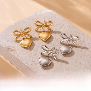Détail de boucles d'oreilles nœud et cœur en or et argent avec des ombres de fleurs