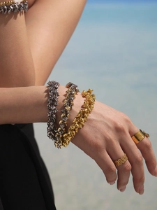 Outdoor lifestyle view of stacked gold and silver thorn texture bracelets and rings