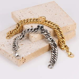 Detailed view of skull-decorated gold and silver Cuban chain bracelets with lobster clasps