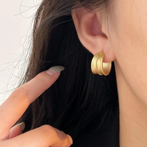 Minimalist matte gold sterling silver chunky hoop earrings worn by a model in soft light