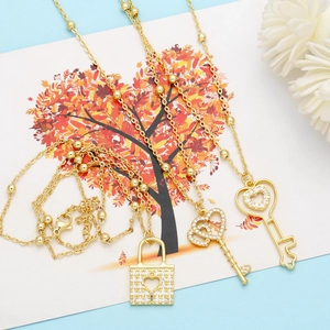 Close-up of heart key and lock pendants in gold finish with micro-inlaid sparkling zircons