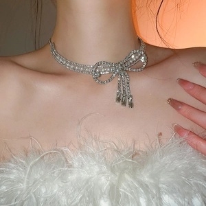 Detail shot of a model wearing a silver bow necklace with elegant pearls and sparkling rhinestones