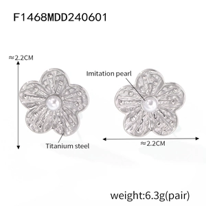 Detailed view of silver flower earrings with hammered texture and imitation pearl center