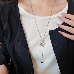 Detail of long silver necklace with flower pendant and amber gemstone on model