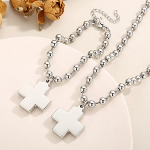 Detail view of two silver cross necklaces with round bead chains on a white base