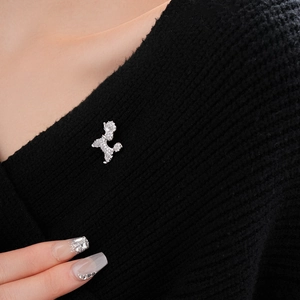 Detailed close-up of a zircon puppy brooch pinned on a black knit sweater collar
