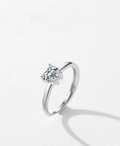 Top down macro view of heart shaped zircon silver ring on white textured paper