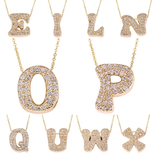 Detail of gold letter pendants with micro-paved cubic zirconia in a cursive font style