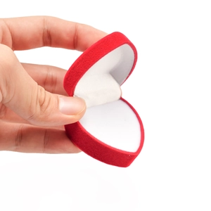 Red heart-shaped velvet jewelry box for rings and earrings shown held by hand
