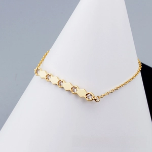Detail of minimalist gold bracelet with five hexagonal zircon pendants on a lobster clasp chain