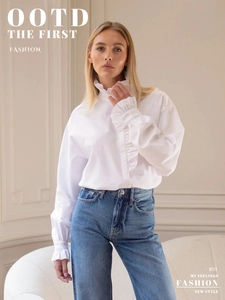 Detail of white ruffled stand collar and elegant pleated cuffs on long sleeve shirt