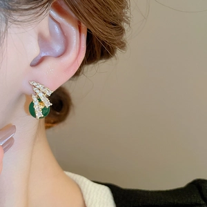 Primo piano di eleganti orecchini a zucca di smeraldo con zirconi su una modella