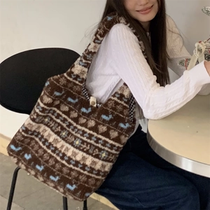 Ethnic plush tote bag with blue heart patterns worn over the shoulder in a cozy cafe