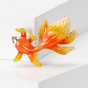 Detailed macro view of an enamel goldfish brooch with orange and yellow gradient finish