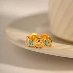 Detail of golden ring with turquoise stones and textured bands on ceramic decor