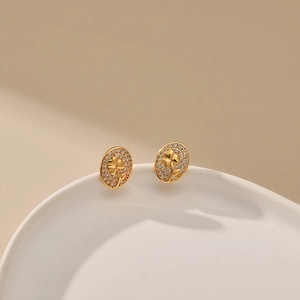 Elegant gold oval stud earrings with engraved flower pattern and zircon accents
