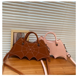 Detail view of gothic bat-shaped PU leather bags with spider web stitching in brown and pink