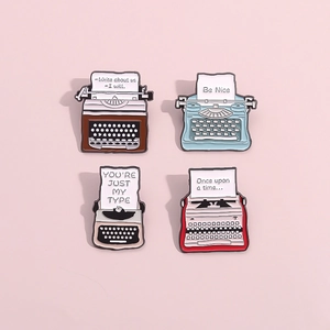 Set of four vintage typewriter enamel pins in brown, blue, beige, and red colors