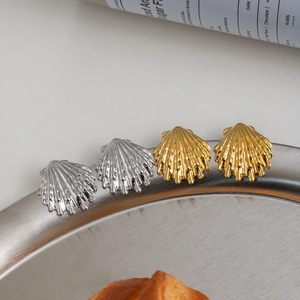 Elegant gold and silver shell earrings set on a stylish metal tray for a chic summer look