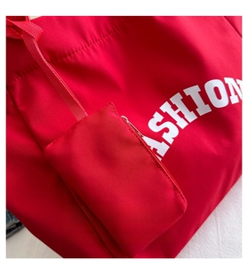 Detail of red nylon tote bag featuring a matching mini zip pouch and white fashion print