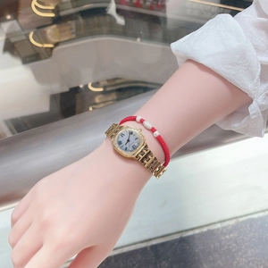 Close-up of women gold quartz watch with H-link steel band and red woven bracelet set
