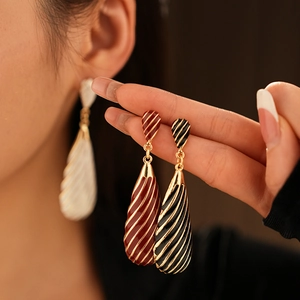 Gros plan détaillé de boucles d'oreilles vintage en émail rayé rouge et noir en gouttes