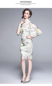 Detail of retro white cheongsam dress featuring green floral lace embroidery and stand collar
