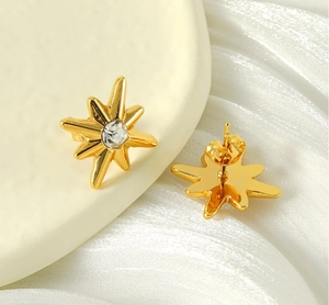 Detail of gold star stud earring with zircon on white silk showing front and back view