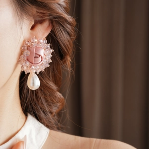Detailed close-up of pink fabric rose earrings with crystals and drop pearl on model