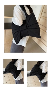 Detail of a large black nylon bow bag showing puffy texture and wide shoulder strap