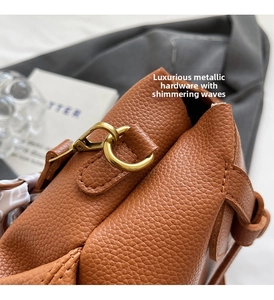 Detail of brown litchi pattern leather bag with vintage gold buckle and silk scarf decoration