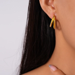 Close-up of a double-layered gold geometric earring with clear rhinestones on model
