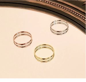 Detail of three slim faceted rings in gold, rose gold and silver on a mirror surface