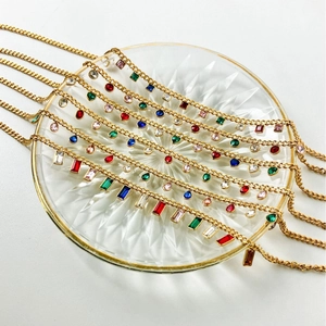 Golden fringe necklaces with colorful crystal pendants displayed on a glass plate